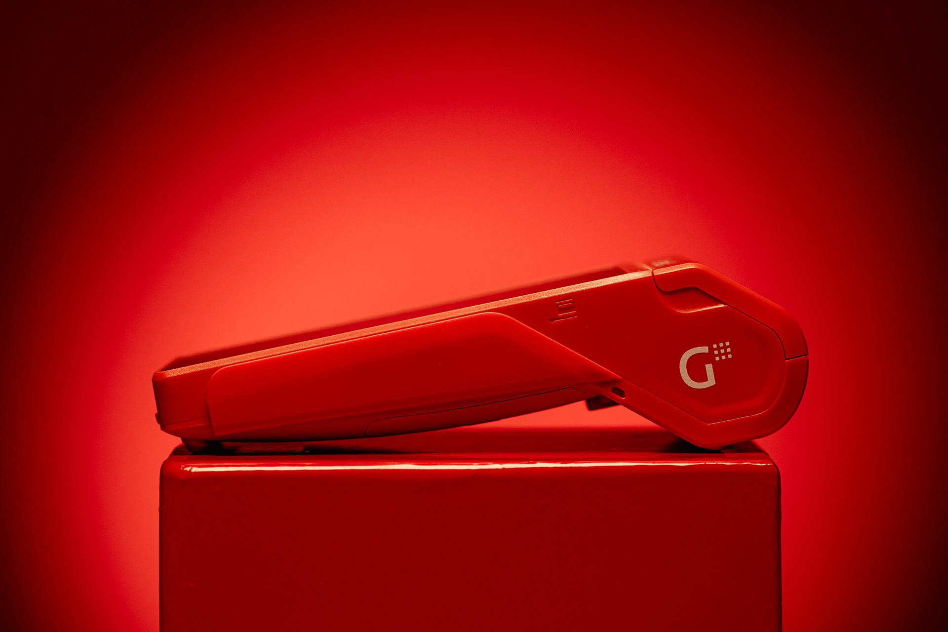 Terminal de cobro roja de Getnet sobre fondo rojo degradado.